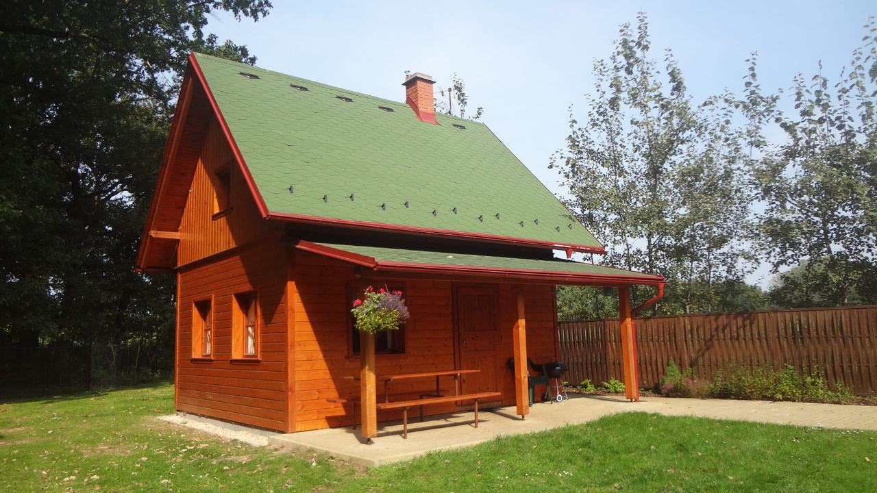 Dřevěná chata č. 3 se zelenou střechou a verandou